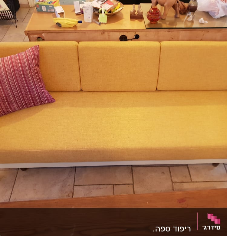 ספה צהובה עם כרית פסים אדומה